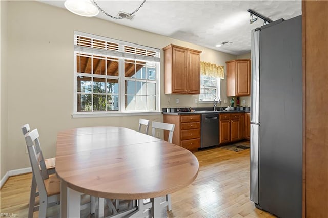 kitchen with visible vents, light wood-style floors, appliances with stainless steel finishes, and brown cabinetry