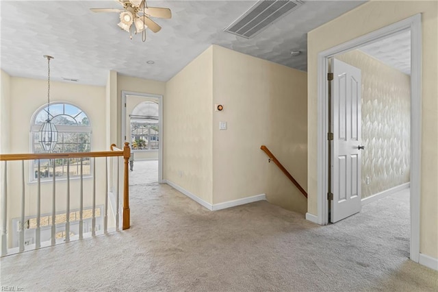 hallway featuring an upstairs landing, visible vents, carpet floors, and baseboards