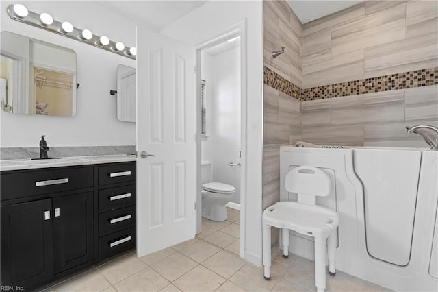 full bath with toilet, a sink, tile walls, tile patterned flooring, and tiled shower