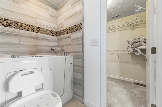 bathroom featuring a walk in closet, washer / dryer, baseboards, and visible vents