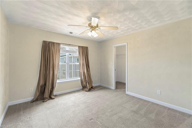 carpeted empty room with visible vents, ceiling fan, and baseboards