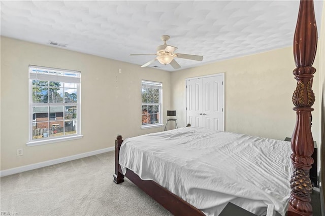 carpeted bedroom with multiple windows, baseboards, visible vents, and a closet