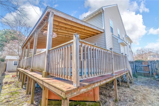 rear view of property with an outbuilding, a wooden deck, a storage shed, and fence