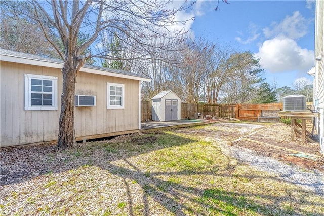 view of yard with a storage shed, an outdoor structure, a fenced backyard, and central AC