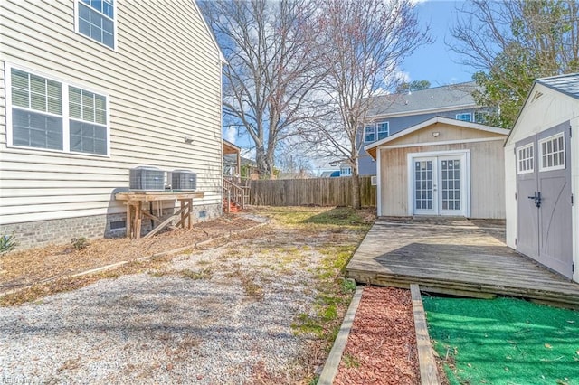 view of yard with a deck, an outdoor structure, french doors, and fence