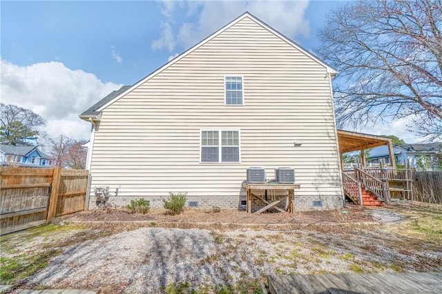 back of house featuring crawl space, central AC unit, stairway, and fence