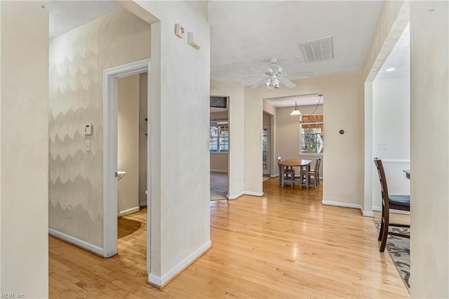 hallway featuring visible vents, light wood-type flooring, and baseboards