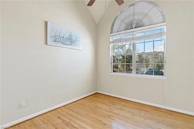 spare room with a ceiling fan, lofted ceiling, wood finished floors, and baseboards