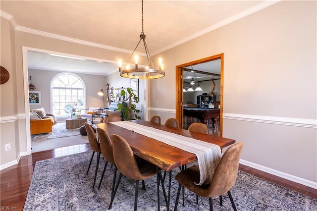 dining area with baseboards, a notable chandelier, wood finished floors, and crown molding