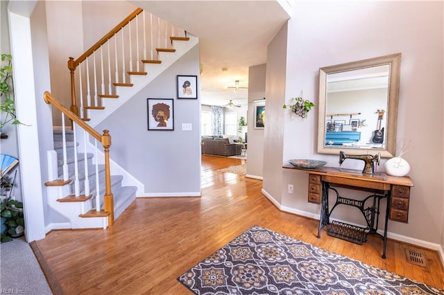 foyer entrance featuring visible vents, baseboards, and wood finished floors