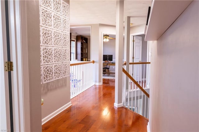 corridor featuring an upstairs landing, baseboards, and wood-type flooring