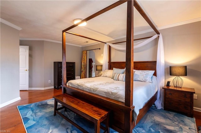 bedroom with wood finished floors, baseboards, and ornamental molding