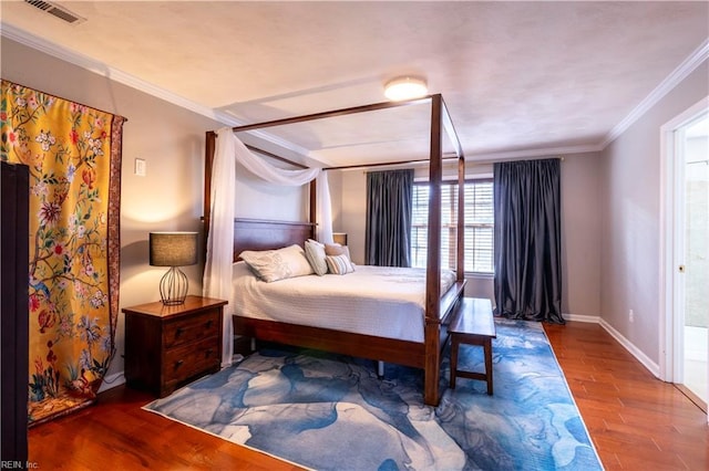 bedroom featuring visible vents, baseboards, wood finished floors, and crown molding