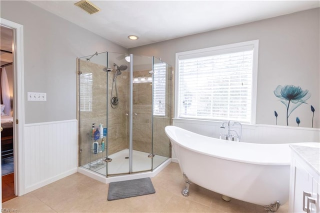 full bath featuring a wainscoted wall, visible vents, a freestanding tub, a stall shower, and tile patterned flooring