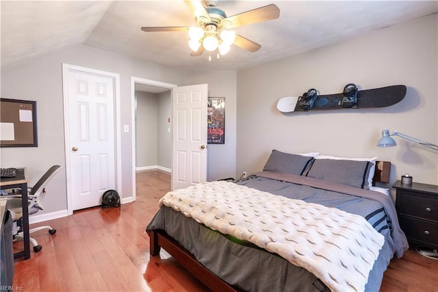 bedroom featuring a ceiling fan, lofted ceiling, wood finished floors, and baseboards