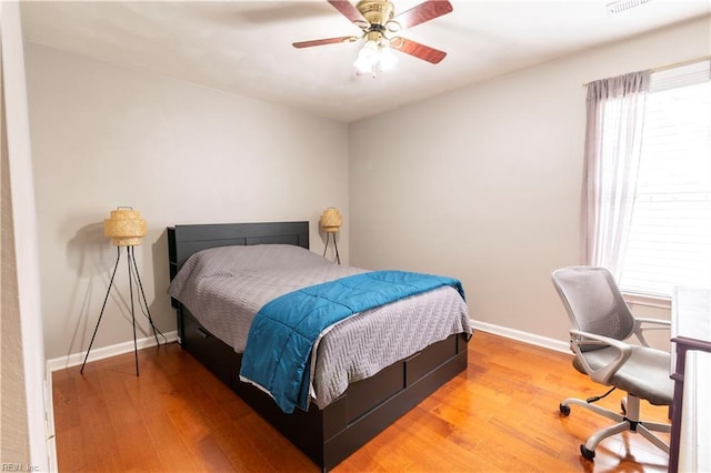 bedroom featuring baseboards, wood finished floors, and a ceiling fan