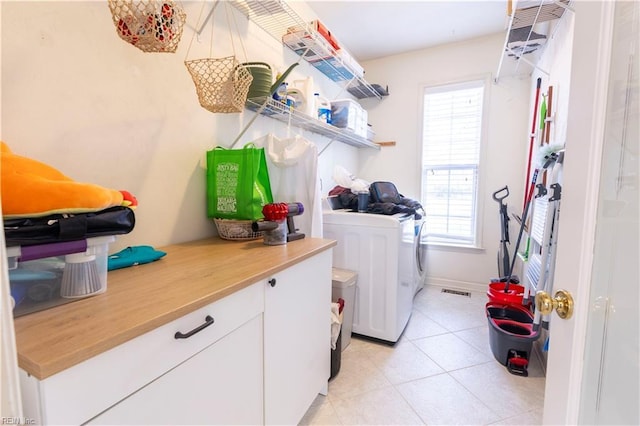 laundry area with washing machine and clothes dryer, laundry area, baseboards, and light tile patterned floors