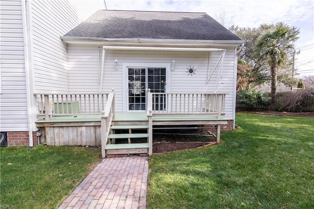 back of property with a lawn, a wooden deck, and roof with shingles