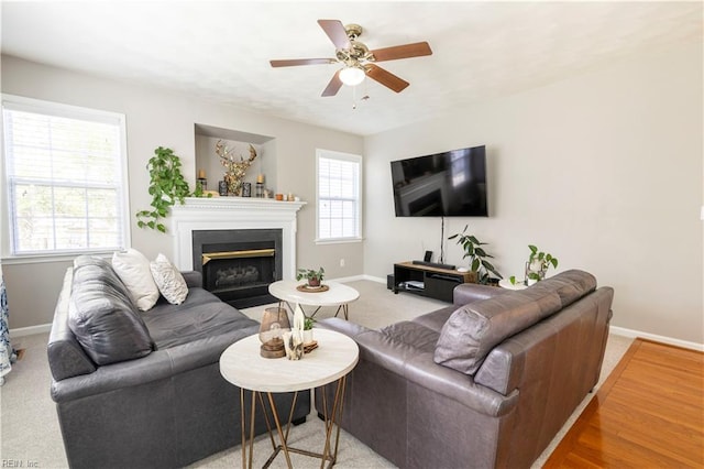 living room with plenty of natural light, a ceiling fan, baseboards, and a fireplace with flush hearth