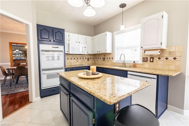 kitchen with a sink, blue cabinets, white appliances, and white cabinets