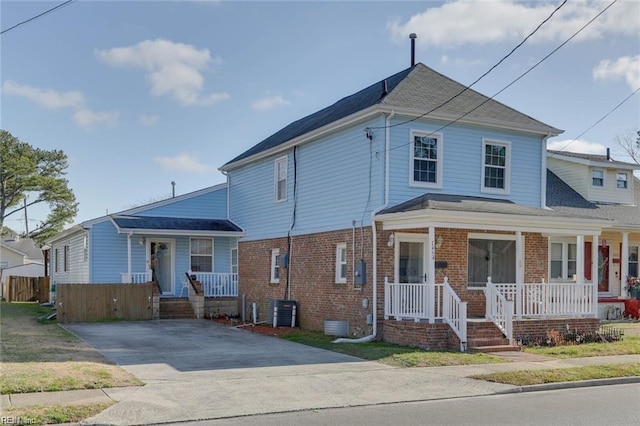 view of front of property featuring a porch, fence, central AC unit, and brick siding