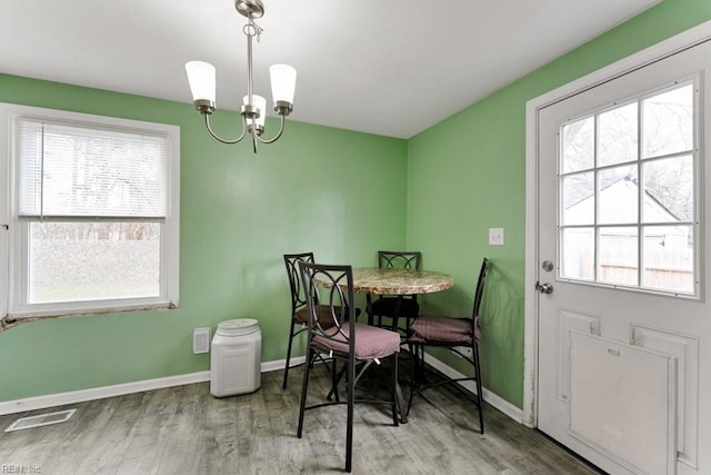 dining room with light wood-style flooring, a notable chandelier, baseboards, and visible vents