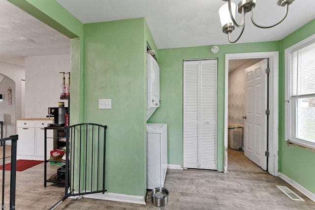 interior space with visible vents, plenty of natural light, wood finished floors, and stacked washer / drying machine