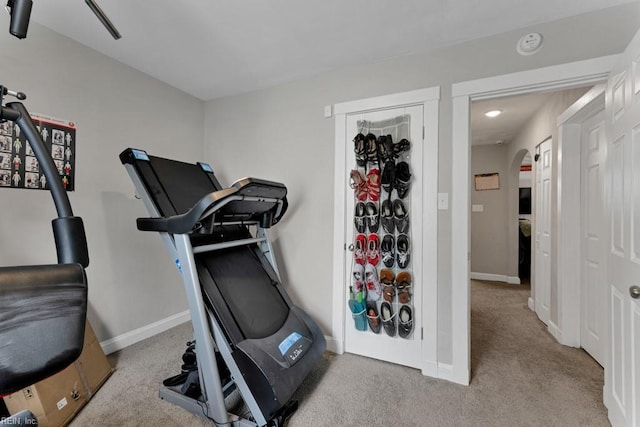 workout room with carpet, arched walkways, and baseboards