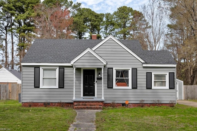 bungalow-style home with a chimney, roof with shingles, a front yard, and fence