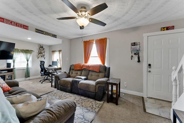 carpeted living area featuring ceiling fan and baseboards