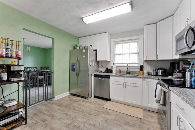 kitchen featuring a sink, light wood-style floors, appliances with stainless steel finishes, and white cabinetry