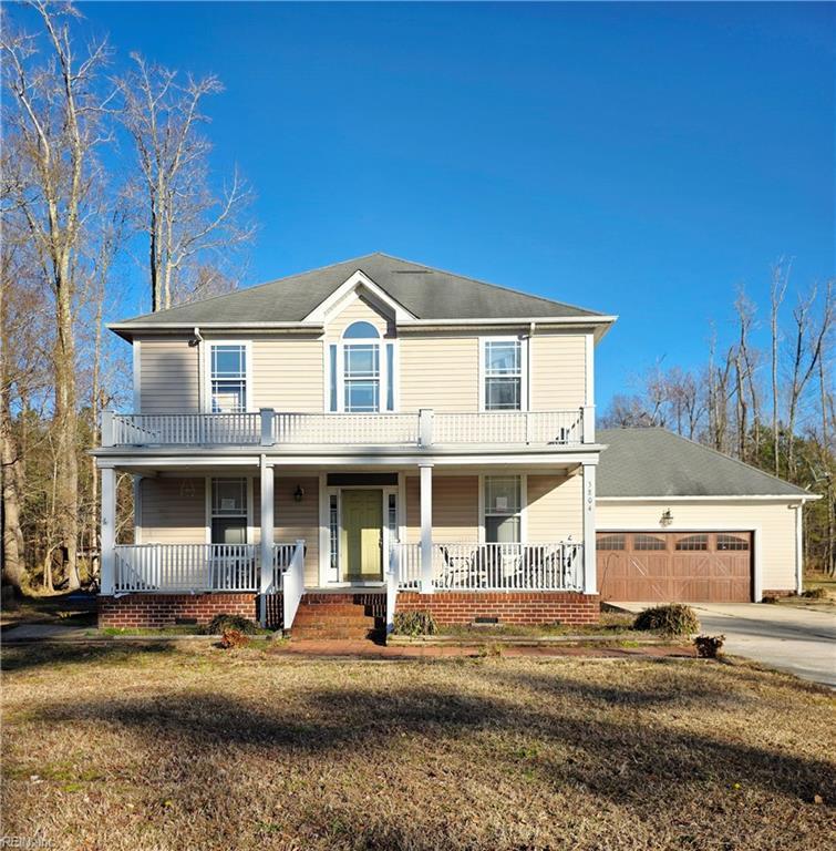 view of front facade with a front lawn, a garage, covered porch, and driveway