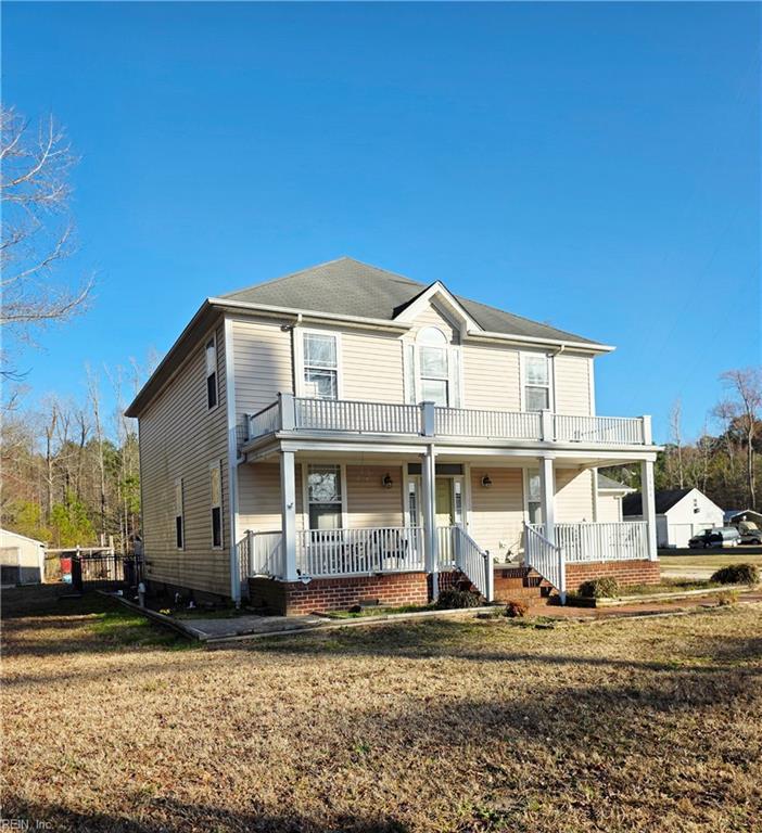 view of front of property featuring a front yard, a balcony, and covered porch