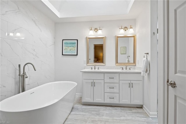 bathroom featuring a freestanding bath, double vanity, and a sink