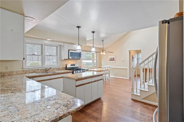 kitchen featuring light wood-type flooring, pendant lighting, light stone counters, white cabinetry, and stainless steel appliances