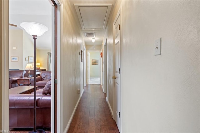 hallway featuring visible vents, attic access, baseboards, and wood finished floors