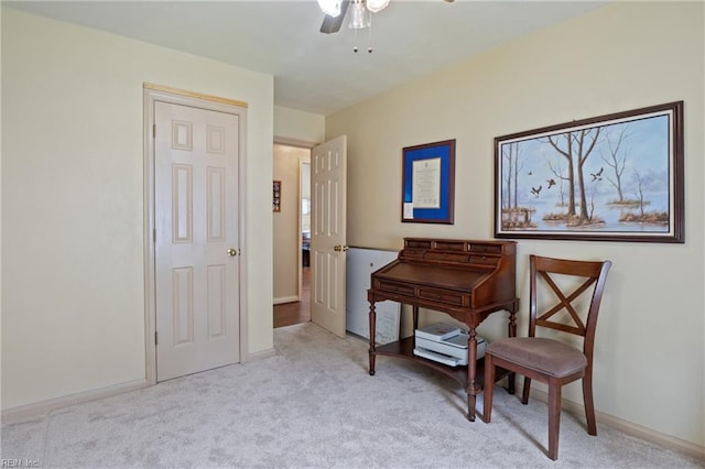 living area featuring baseboards, light colored carpet, and ceiling fan