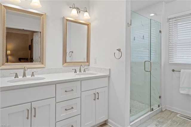 full bath with a sink, visible vents, a marble finish shower, and double vanity