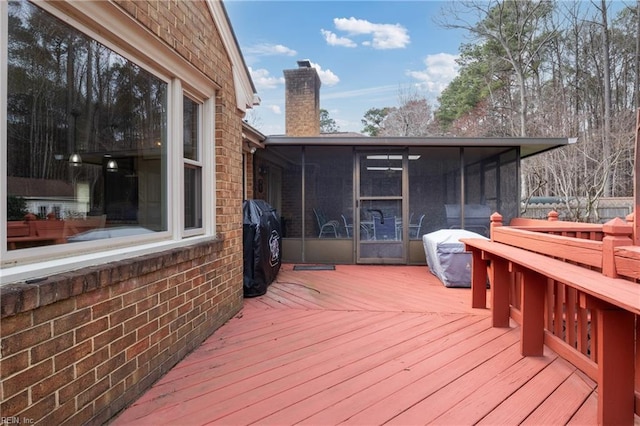 deck with a grill and a sunroom