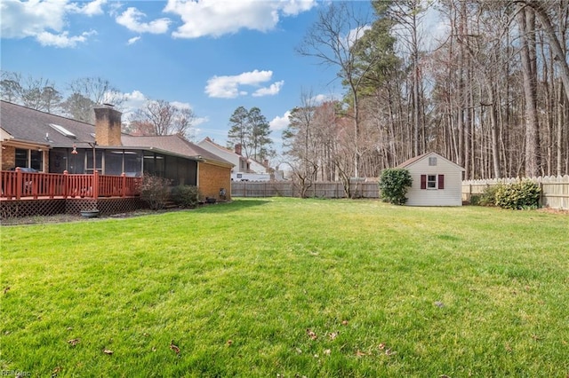 view of yard featuring an outbuilding, a fenced backyard, and a sunroom