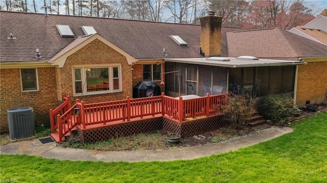 rear view of property with roof with shingles, a sunroom, a chimney, central air condition unit, and brick siding