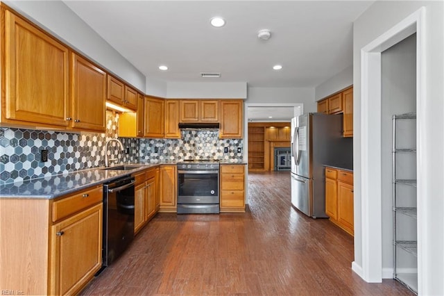 kitchen featuring a sink, decorative backsplash, dark wood-type flooring, under cabinet range hood, and appliances with stainless steel finishes