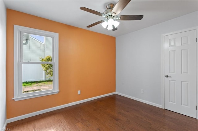 spare room featuring baseboards, dark wood-type flooring, and ceiling fan