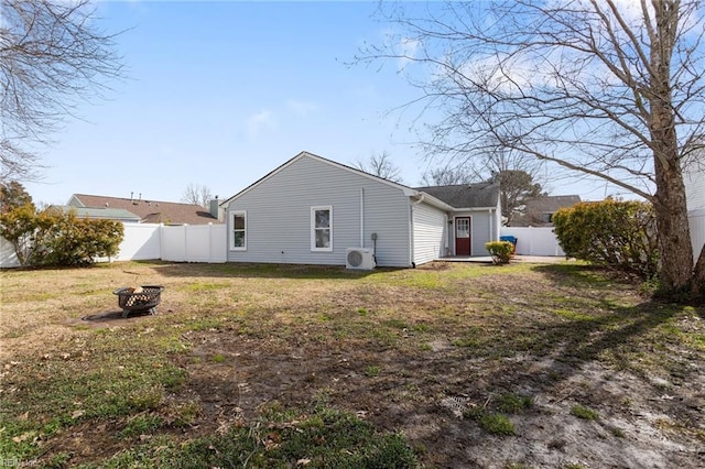 back of house featuring a yard, an outdoor fire pit, a fenced backyard, and ac unit