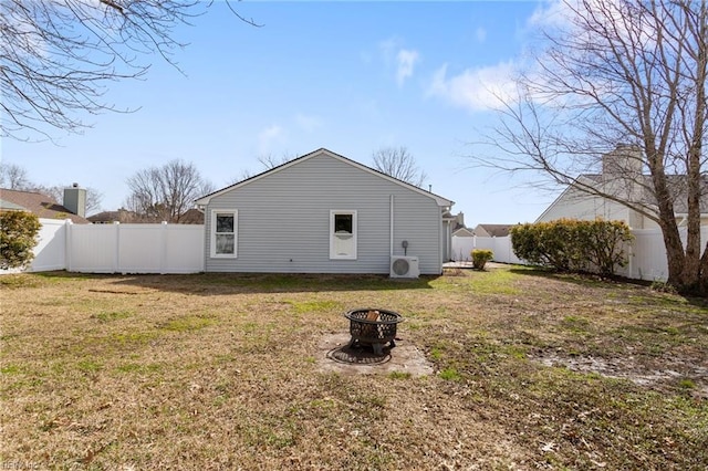 back of property featuring ac unit, a fire pit, a fenced backyard, and a lawn