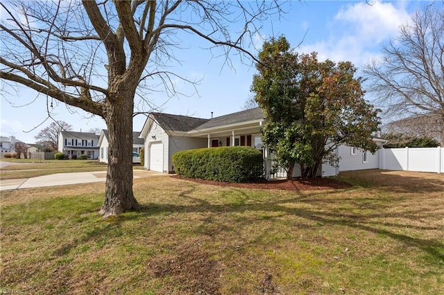 view of front of house featuring an attached garage, concrete driveway, a front lawn, and fence