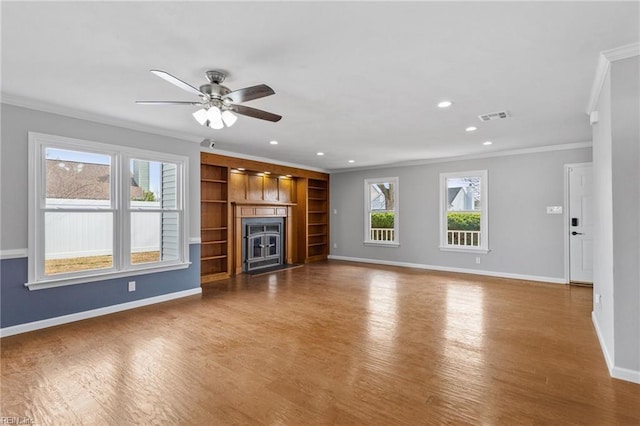 unfurnished living room with visible vents, baseboards, wood finished floors, and crown molding