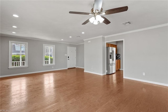 unfurnished living room with crown molding, wood finished floors, visible vents, and baseboards