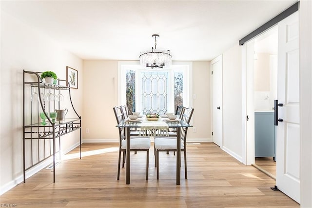 dining area featuring a notable chandelier, light wood-style flooring, and baseboards
