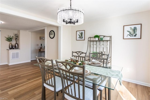 dining room featuring visible vents, baseboards, an inviting chandelier, and wood finished floors